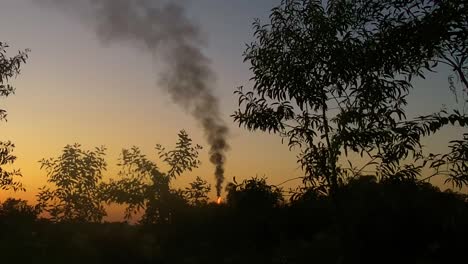 Flame-and-black-smokes-rising-from-rural-village-in-Ukraine,-vibrant-sunset-time
