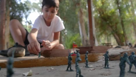 A-boy-plays-alone-with-plastic-green-army-men-at-the-park