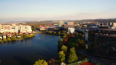 Aerial-drone-shot-over-Cluj-Napoca-city,-Iulius-mall-zone,-Iulius-park,-and-lake-view