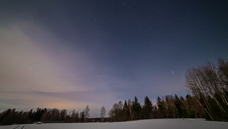 Time-lapse-of-night-starry-sky-in-a-snowy-field-near-a-forest-with-wide-copy-space