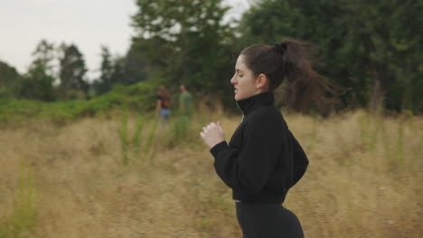 White-woman-in-black-clothing-running-on-a-trail-through-a-field