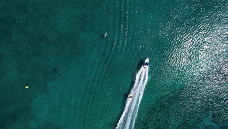 Drone-shot-of-adrenaline-water-sport-towable-tube-ring-with-speed-boat-action-on-calm-sea