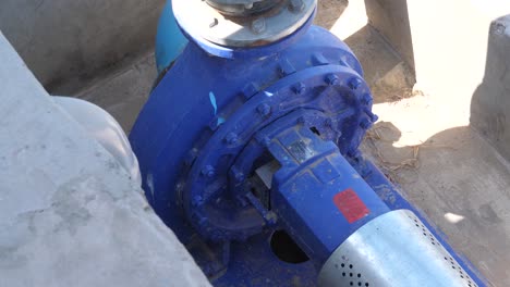High-angle-shot-over-a-blue-diesel-pump-used-for-drawing-water-from-a-nearby-water-body-to-irrigate-the-nearby-fields