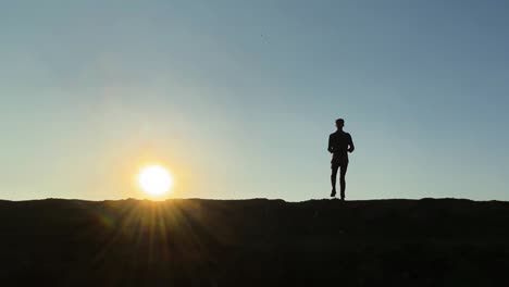Silhouetted-young-man-jogging-on-the-spot-against-sunset
