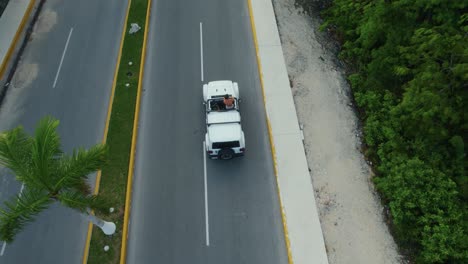 Drone-shot-view-of-white-cars-driving-on-road-in-Tulum-city,-Mexico