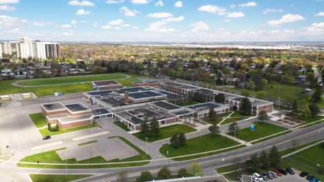Drone-circling-around-school-with-solar-panels-in-sunny-suburban-neighborhood