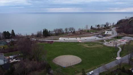Drone-flying-away-from-lakeside-park-in-spring