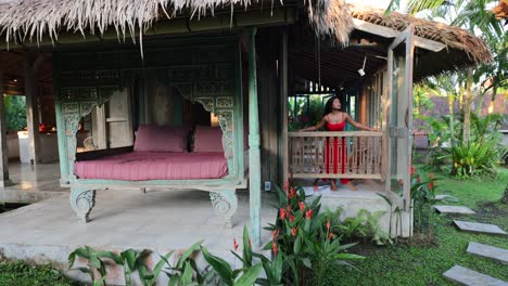 Braunes-Asiatisches-Mädchen,-Das-Sich-Am-Sonnigen-Morgen-In-Einer-Traditionellen-Bali-Villa-Am-Balkonfenster-Lehnt