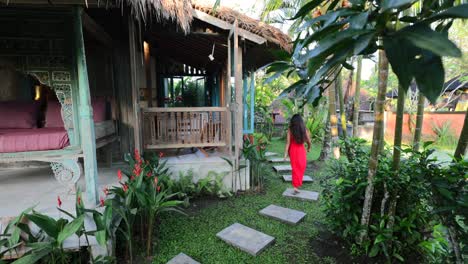Junge-Asiatin-Im-Roten-Kleid,-Die-Auf-Dem-Fußweg-Durch-Den-Tropischen-Garten-In-Der-Traditionellen-Bali-villa-Geht