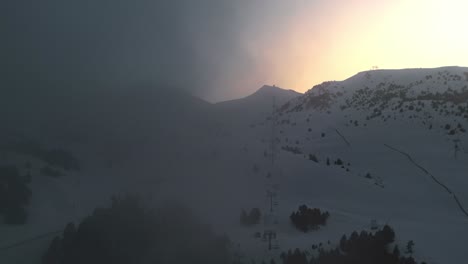 Drone-flying-through-cloud-at-a-snowy-mountain-ski-resort-during-golden-hour