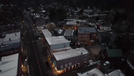 Early-morning-rising-aerial,-town-of-Woodstock,-Vermont-with-cars-passing-by-on-cold-winter-day