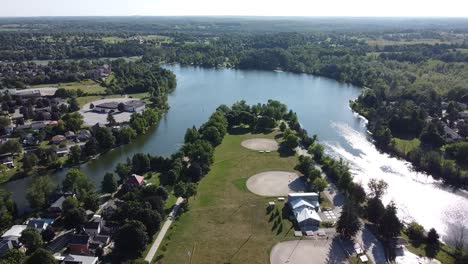 Drone-circling-over-a-park-next-to-a-lake-during-a-summer-day
