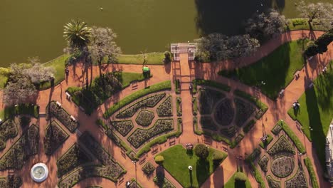 Aerial-top-down-shot-of-green-cart-driving-at-Rosedal-of-Palermo-Park-of-Buenos-Aires-near-lake-during-sunny-day