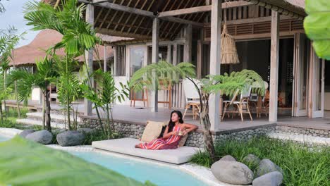Cámara-Lenta-De-Una-Mujer-Asiática-Relajándose-Junto-A-La-Piscina-En-Una-Lujosa-Villa-Bohemia-En-Bali-En-Un-Día-Nublado