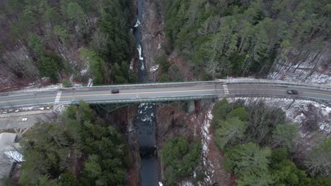 Ottauquechee-River-Gorge,-rising-aerial-in-Quechee-Vermont,-cars-drive-over-bridge