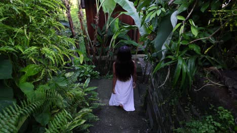 Cámara-Lenta-De-Una-Chica-Asiática-Con-Vestido-Blanco-Caminando-Abajo-A-Través-De-Un-Jardín-En-Bali-Indonesia