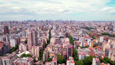 Dolly-in-aerial-view-of-residential-buildings-in-the-Almagro-neighborhood-on-a-sunny-day,-the-skyline-of-Puerto-Madero-is-seen-in-the-background,-Argentina