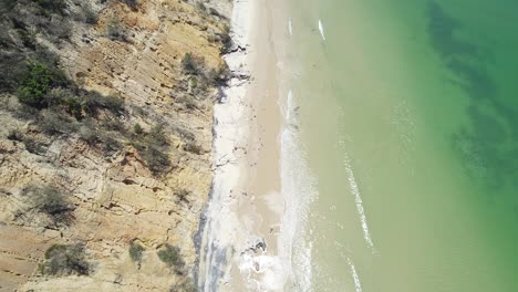 Waves-Splashing-On-White-Sandy-Shore-With-Rocky-Cliffs-In-Rainbow-Beach,-Queensland,-Australia