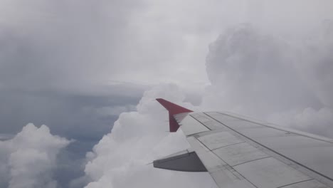 Blick-Auf-Den-Himmel-Durch-Das-Flugzeugfenster-Beim-Fliegen-über-Die-Flauschige-Wolkenhimmellandschaft-Tagsüber-Mit-Flügelansicht,-Luftaufnahme-über-Den-Wolken-Und-Himmel-Inspirationskonzept,-Natürlicher-Hintergrund-Cloudscape