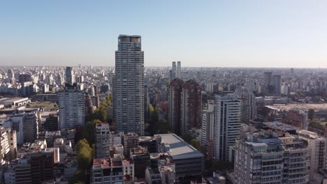 Aerial-approaching-shot-of-large-Le-Parc-Skyscraper-surrounded-by-high-rise-buildings-in-downtown-of-Buenos-Aires-during-sunset-time