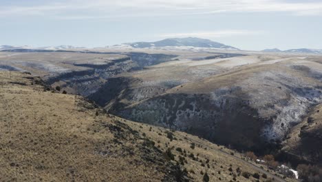 Eine-Drohne-Fliegt-Mit-Schnee-über-Einen-Grasbewachsenen-Bergrücken-Im-Ländlichen-Idaho