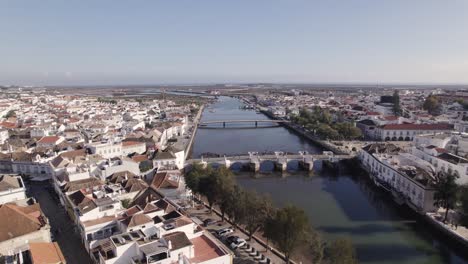 Orbiting-view-of-Old-bridge-over-Gilao-river-from-Tavira,-Downtown-white-riverside-houses
