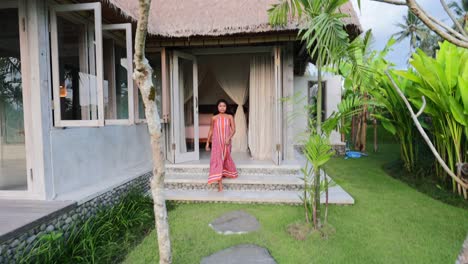 Junges-Asiatisches-Mädchen-In-Schönem-Kleid,-Das-An-Einem-Sonnigen-Morgen-In-Bali-Vom-Eingang-Der-Villa-Zum-Garten-Im-Freien-Geht