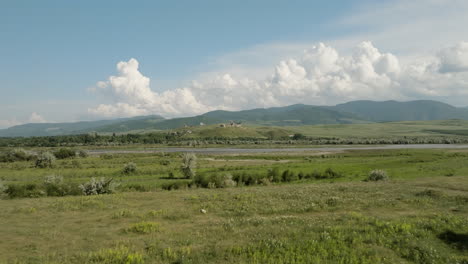 Riverside-meadow-landscape-in-Georgia,-Samtsevrisi-castle-in-distance