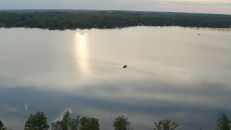 Aerial,-small-personal-fishing-boat-on-a-calm-lake-in-the-morning