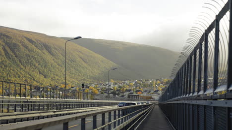 Tráfico-Y-Pasarela-Peatonal-En-El-Puente-Tromso-Durante-El-Otoño-En-Noruega-Con-Paisajes-Montañosos-Lejanos