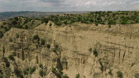 Arid-sand-desert-cliff-and-hilly-steppe-with-bushy-vegetation,-Georgia