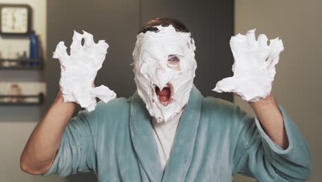 Portrait-of-a-man-with-foam-on-his-face-and-hands-scaring-into-the-camera