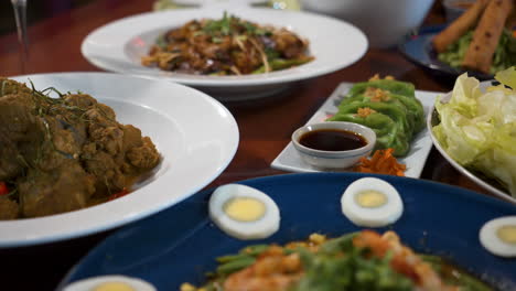 Eine-Tischplatte-Gefüllt-Mit-Asiatischem-Essen,-Viele-Einzigartige-Thailändische-Gerichte-Auf-Dem-Restauranttisch,-Schieberegler-Nahaufnahme-4k