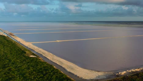 sunshine-reflecting-off-the-water-at-Las-Coloradas-pink-lakes-during-sunset-with-dark-blue-clouds