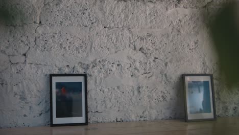 Zwei-Bilder-Gerahmt,-Auf-Einem-Holzboden,-An-Eine-Weiße-Backsteinwand-Gelehnt,-In-Einem-Leeren-Raum