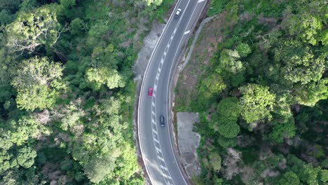 Top-down-drone-shot-following-cars-driving-along-mountain-road