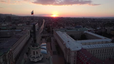 Sonnenuntergang-drohnenansicht-Des-Bulgarischen-Parlaments-In-Sofia,-Nationalversammlung-Zeigt-Bulgarische-Flagge-über-Skyline