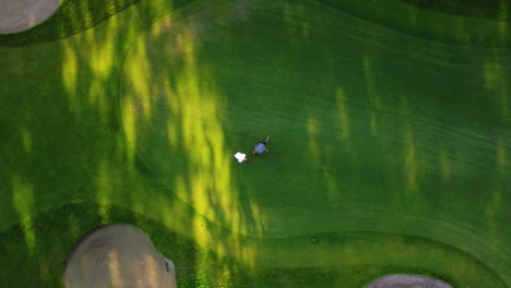 Drohnenaufnahme-Von-Oben-Auf-Dem-Golfplatz-An-Einem-Sonnigen-Tag-Mit-Golfern,-Die-Den-Golfball-Setzen