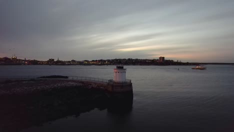 Portland-Breakwater-Lighthouse,-Bug-Light-at-sunset,-aerial-cinematic-pull-away-in-Portland,-Maine