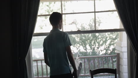 Young-man,-teenage-boy-watches-out-window
