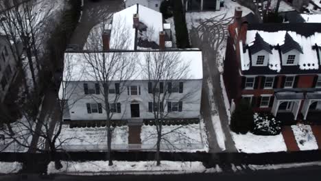 Historic-downtown-homes-in-Woodstock,-Vermont-in-winter-in-snow---aerial-flyover