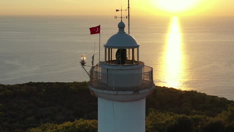 Aerial-View-of-Gelidonya-Lighthouse,-Turkish-Flag-and-Mediterranean-Sea-Horizon-at-Sunset