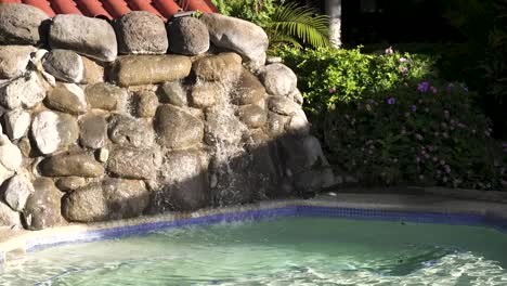Artificial-cement-rock-cascade-and-pool-at-resort-in-San-Jose-Costa-Rica,-Handheld-medium-shot