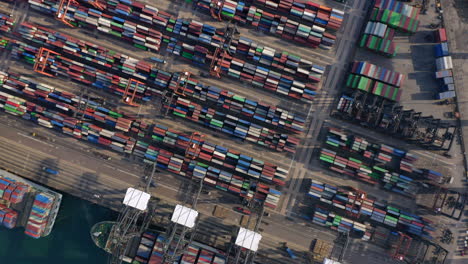Multiple-stack-cranes-moving-over-the-container-yard-while-trucks-drive-towards-the-deep-sea-cranes