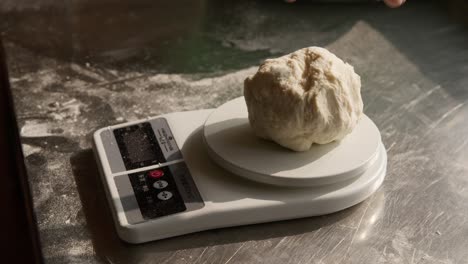 Cook-puts-dough-portion-on-kitchen-food-scales