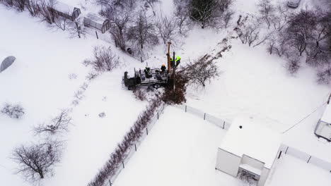 Maintenance-engineer-workers-repairing-electricity-post-on-snowy-rural-farmland-aerial-orbiting-view