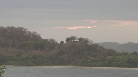 Hills-and-riverbed-in-Costa-Rica-with-sunset-behind-clouds,-Wide-handheld-shot