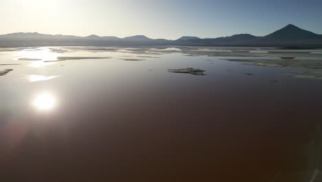Laguna-Colorada,-Aerial-Drone-Above-Red-Lake-Lagoon,-Sun-Reflects-Water,-Bolivia-Travel-and-Tourism,-Unpolluted-Latin-America
