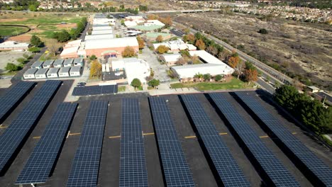 Aerial-Solar-Panels-at-school-parking-lot,-Clean-Energy-Golden-Sunlight