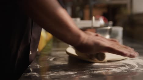 The-dough-rolling-the-man's-hands-on-counter-top-with-flour
